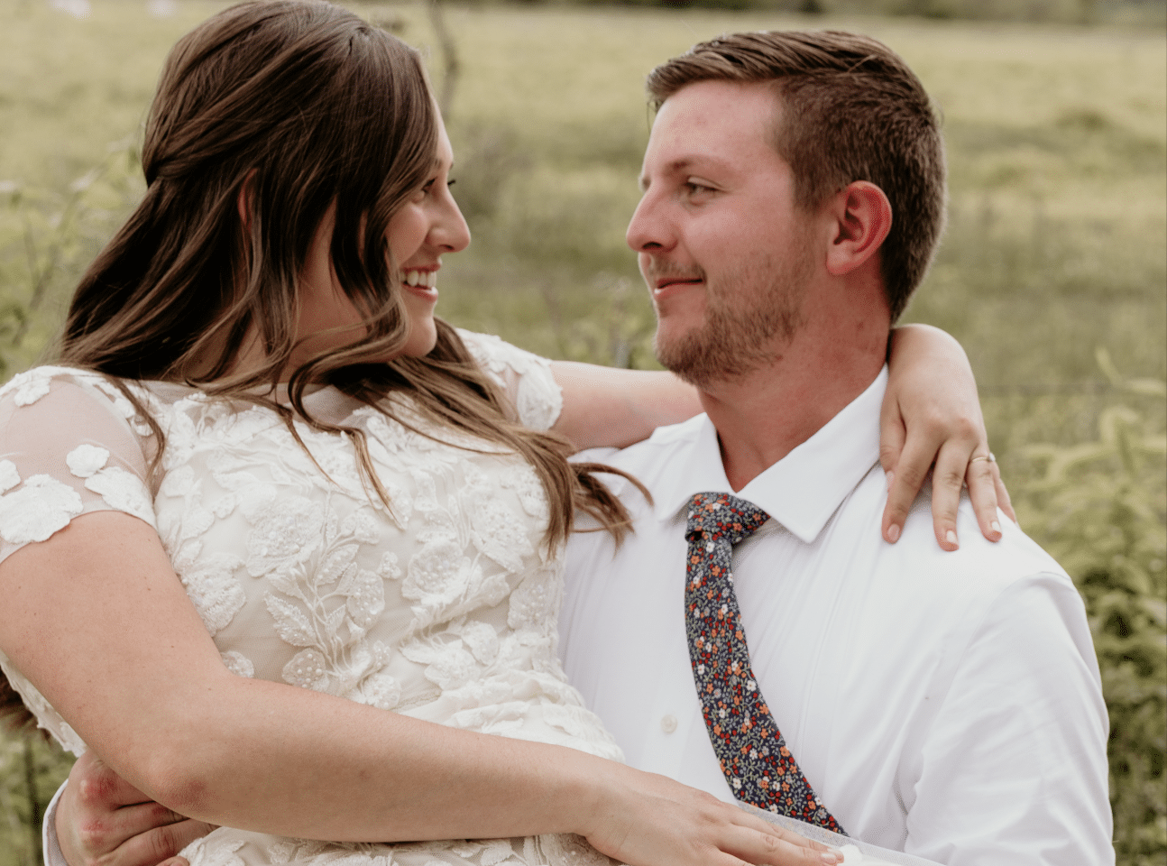 Couple embracing forehead to forehead at golden-hour sunset on a grassy bluff overlooking the water during a Kansas City elopement