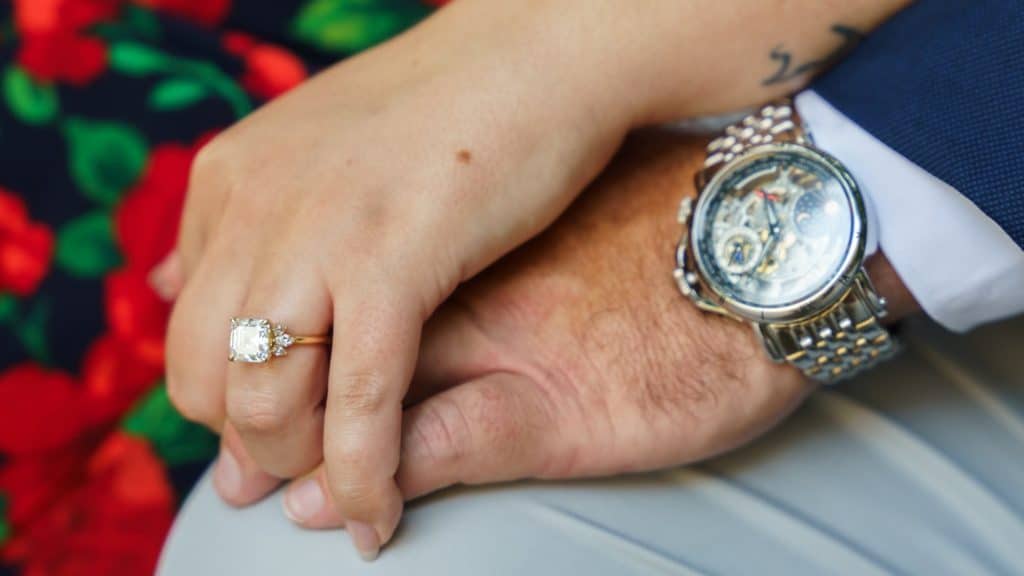 Close-up of a diamond engagement ring as her hand rests on his hand and watch at the Nelson-Atkins in Kansas City