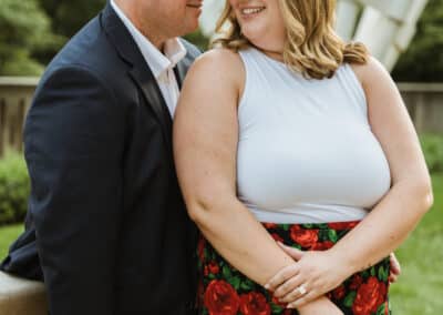 Newly engaged couple stand close and smile at each other in front of a Shuttlecocks sculpture on the Nelson-Atkins lawn