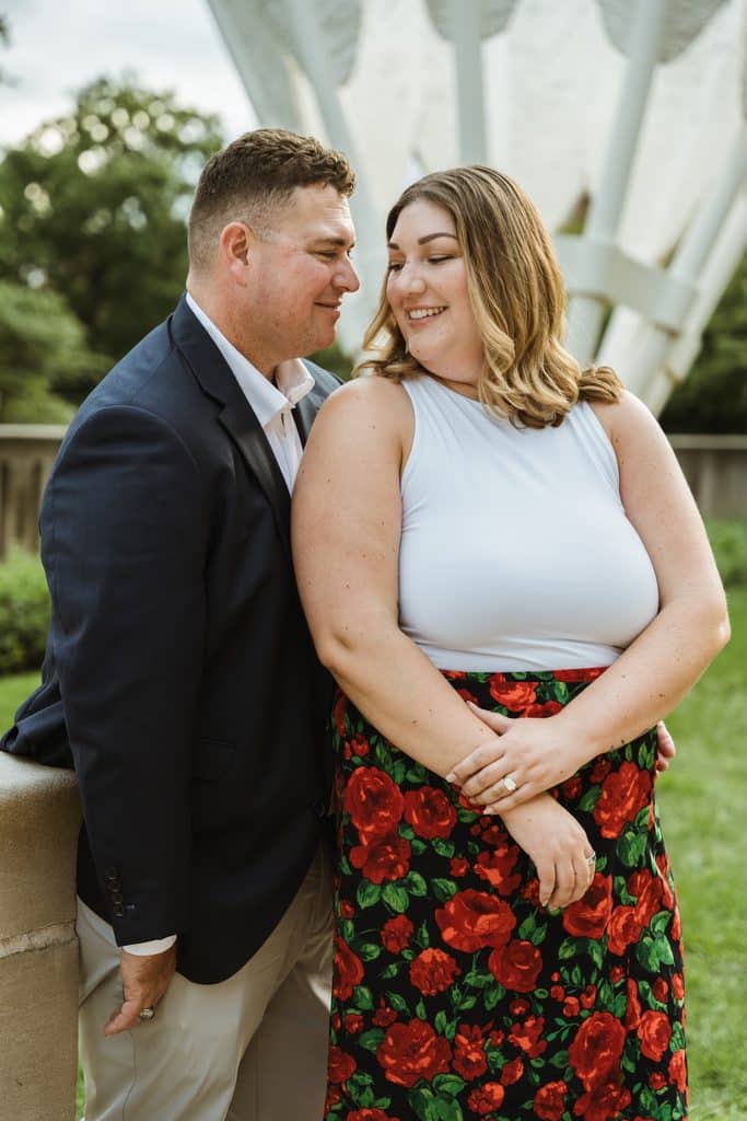 Bride-to-be smiles as her fiance looks at her in front of a Shuttlecock sculpture at the Nelson-Atkins in Kansas City