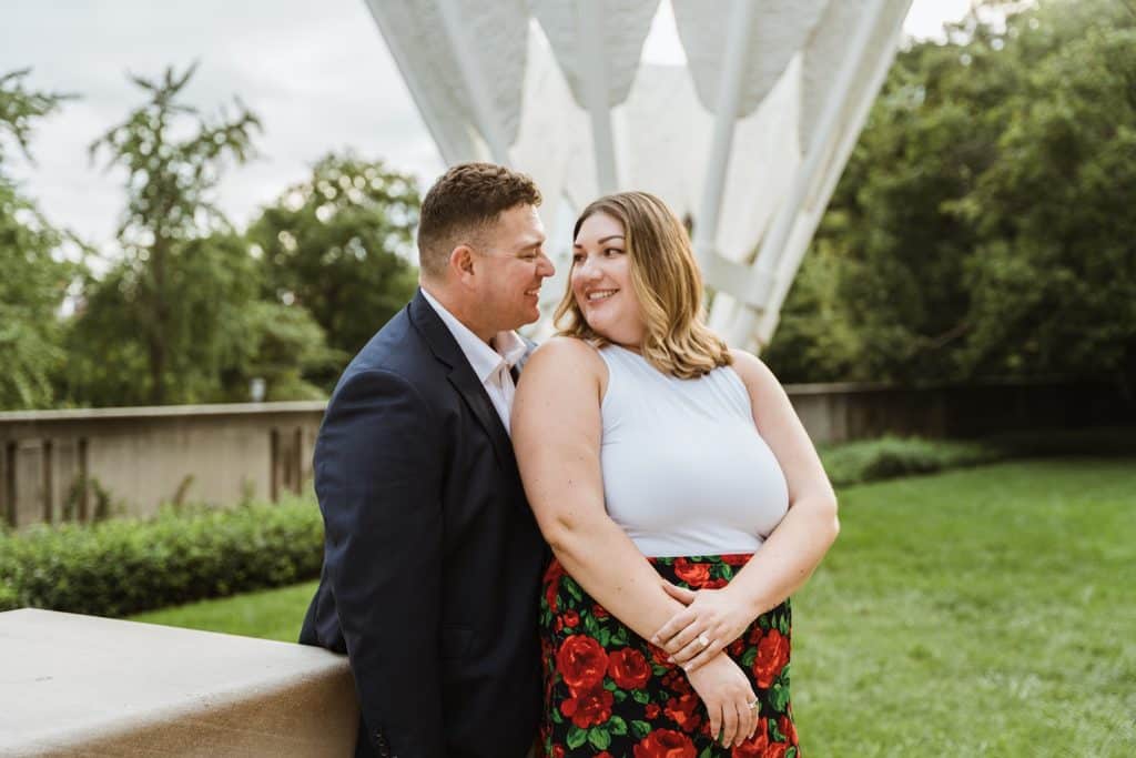 Groom-to-be leans close to his smiling fiancee in front of a Shuttlecock sculpture at the Nelson-Atkins in Kansas City