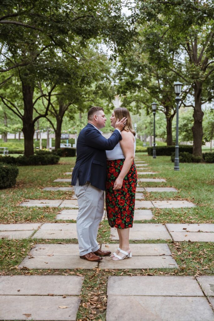 Engaged couple stands forehead to forehead on the tree-lined walkway at the Nelson-Atkins in Kansas City
