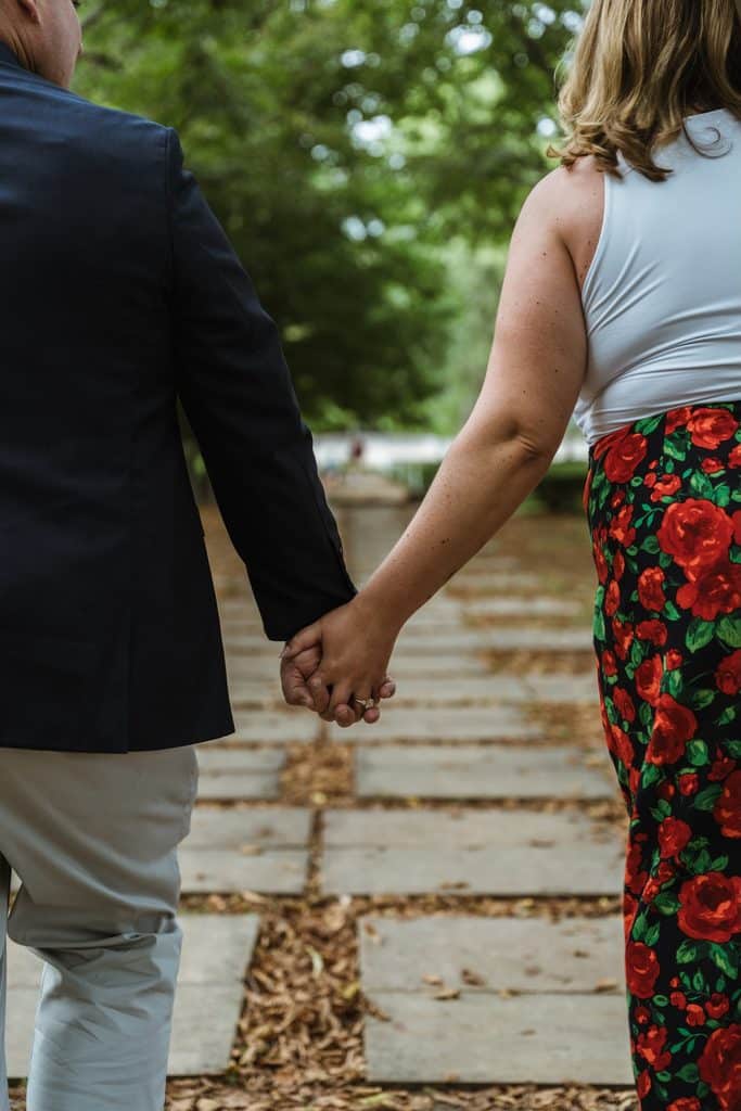 Close-up of an engaged couple holding hands while walking the stone path at the Nelson-Atkins in Kansas City