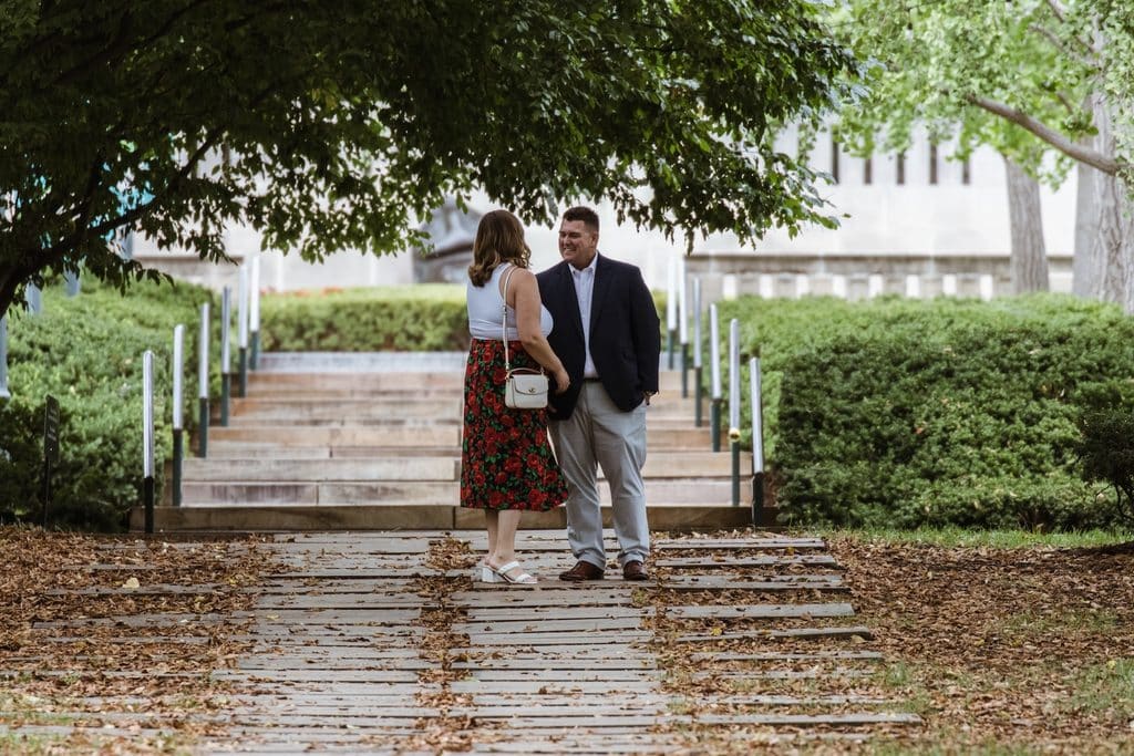 Couple stands together at the foot of the steps on the Nelson-Atkins grounds in Kansas City before the proposal
