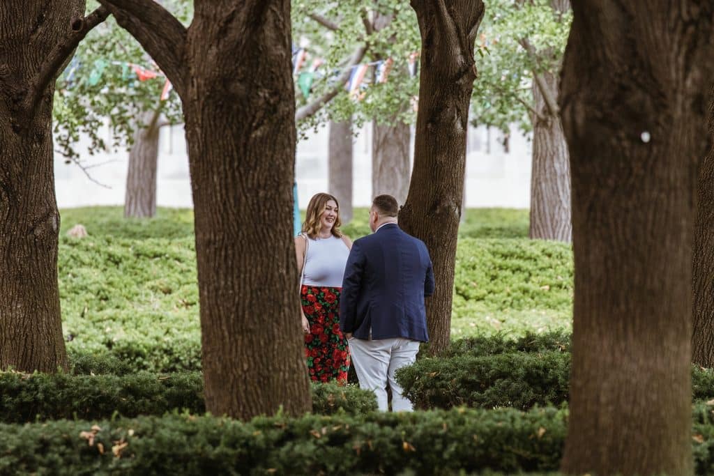 Man faces his girlfriend among the linden trees at the Nelson-Atkins in Kansas City moments before proposing