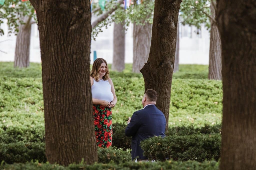 Woman laughs in surprise as her boyfriend kneels with the ring at the Nelson-Atkins in Kansas City