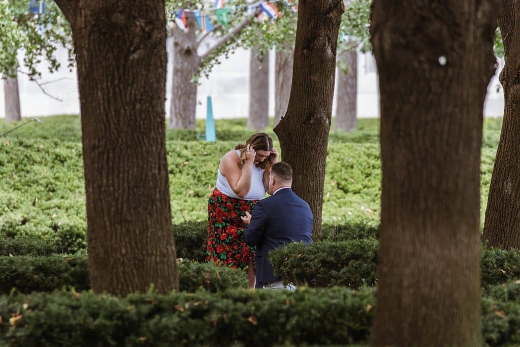 Bride-to-be smiles with her eyes closed while hugging her fiance after the proposal at the Nelson-Atkins in Kansas City